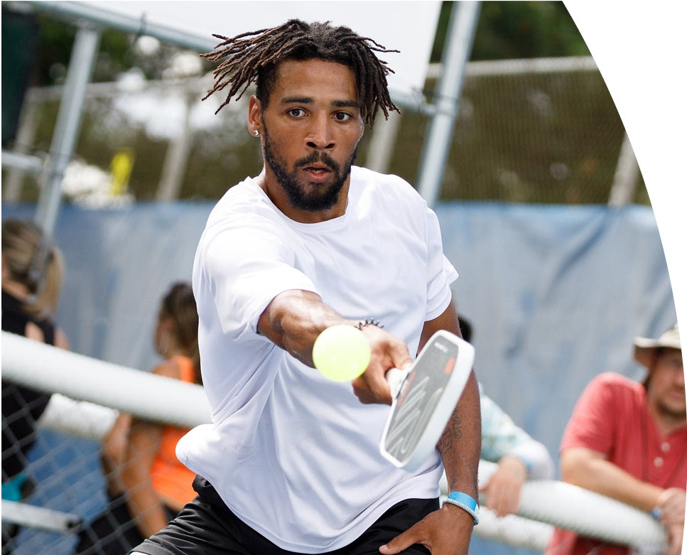 Man playing pickleball with a Revolin paddle on a court with spectators in the background