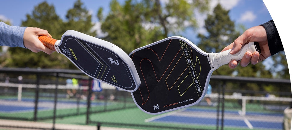 Two Revolin pickleball paddles held by hands with a court in the background