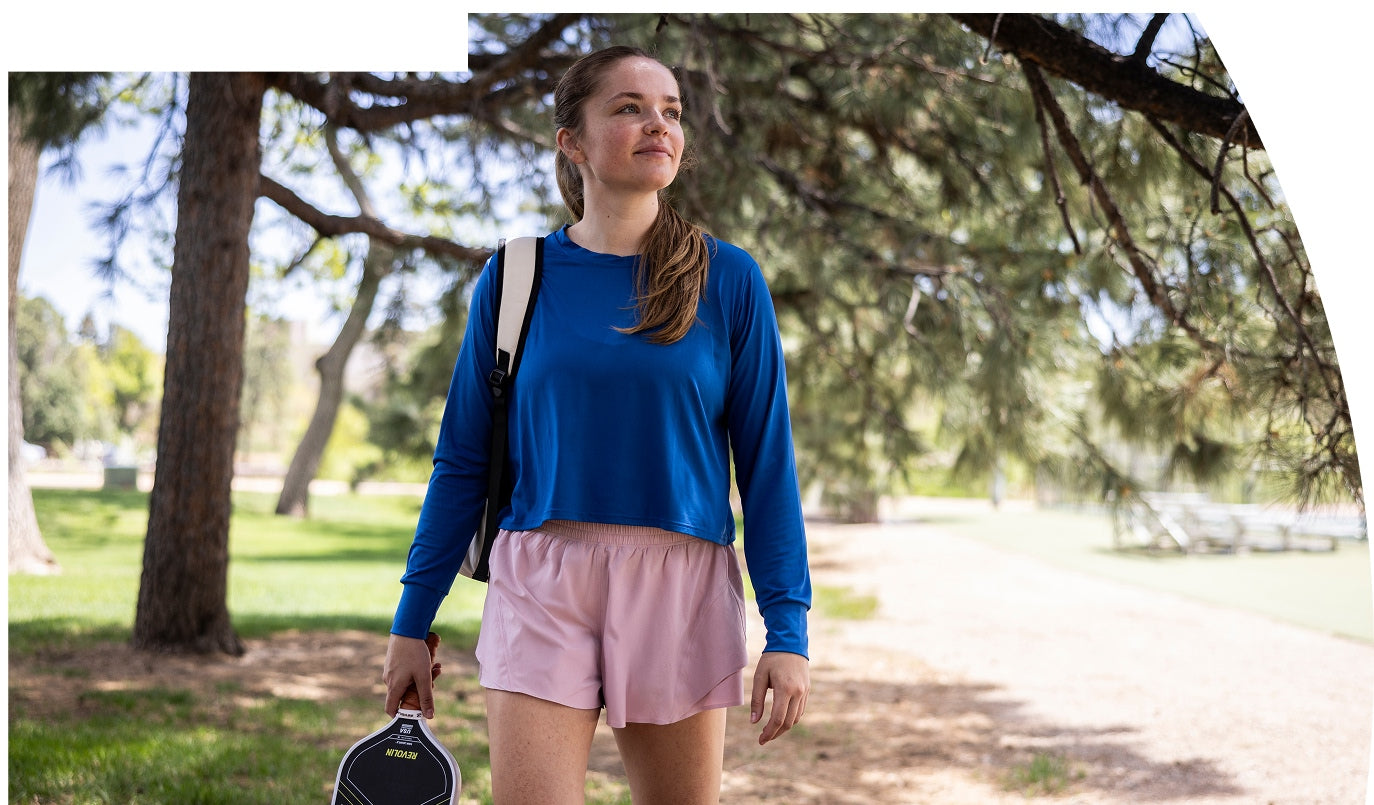 Woman in athletic wear holding a Revolin pickleball paddle in a park